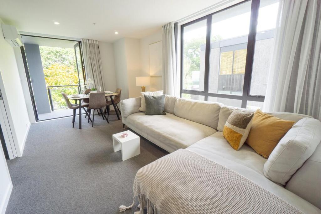 a living room with a white couch and a table at Touch of Class CBD, free park in Christchurch