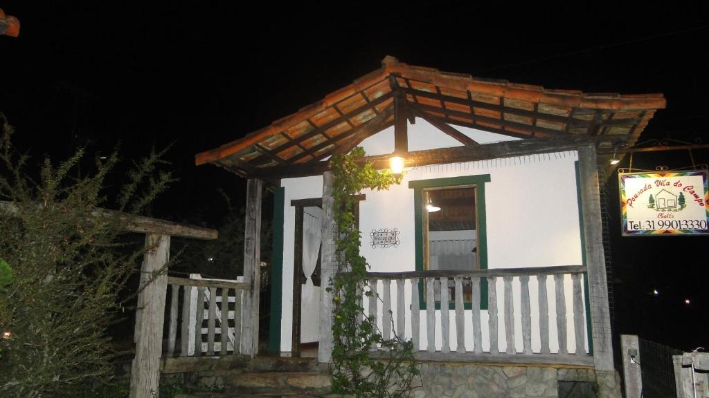 een klein wit gebouw met een veranda in de nacht bij Pousada Vila do Campo in Lavras Novas