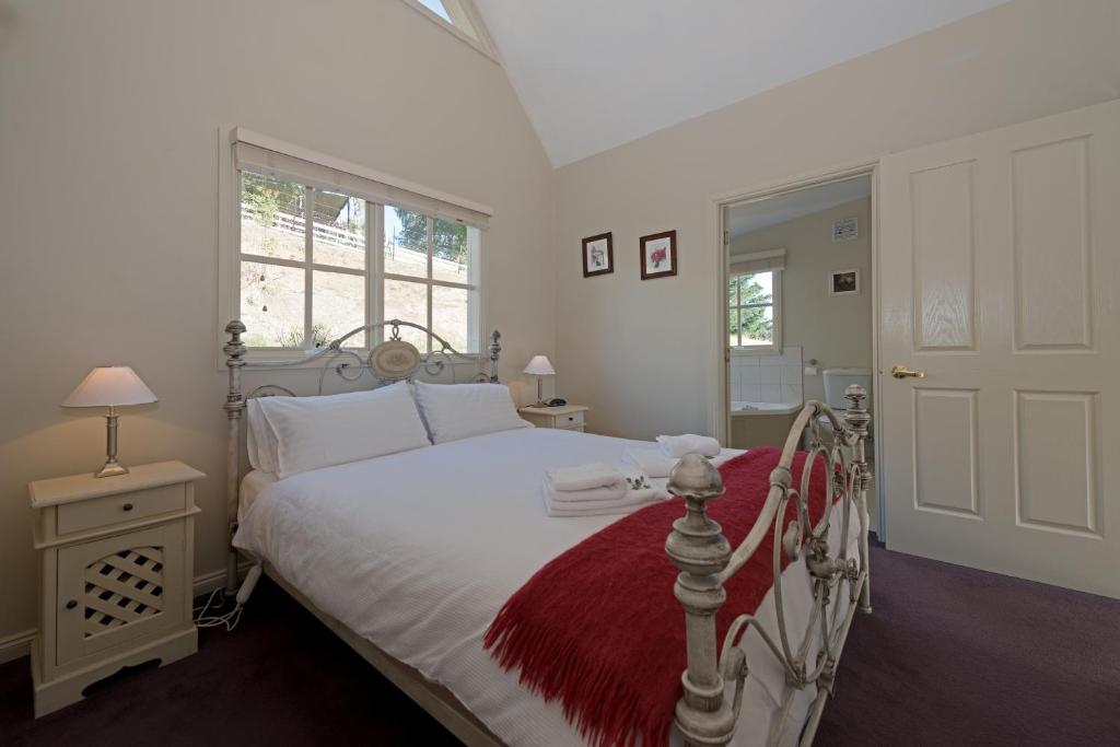 a bedroom with a white bed with a red blanket at Crabtree Riverfront Cottages - Riverfront Relaxation in Grove