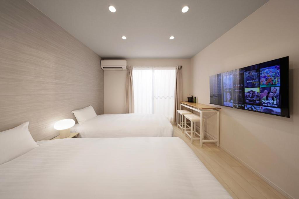 a bedroom with two beds and a tv on the wall at クリスタルコート白浜 in Shirahama