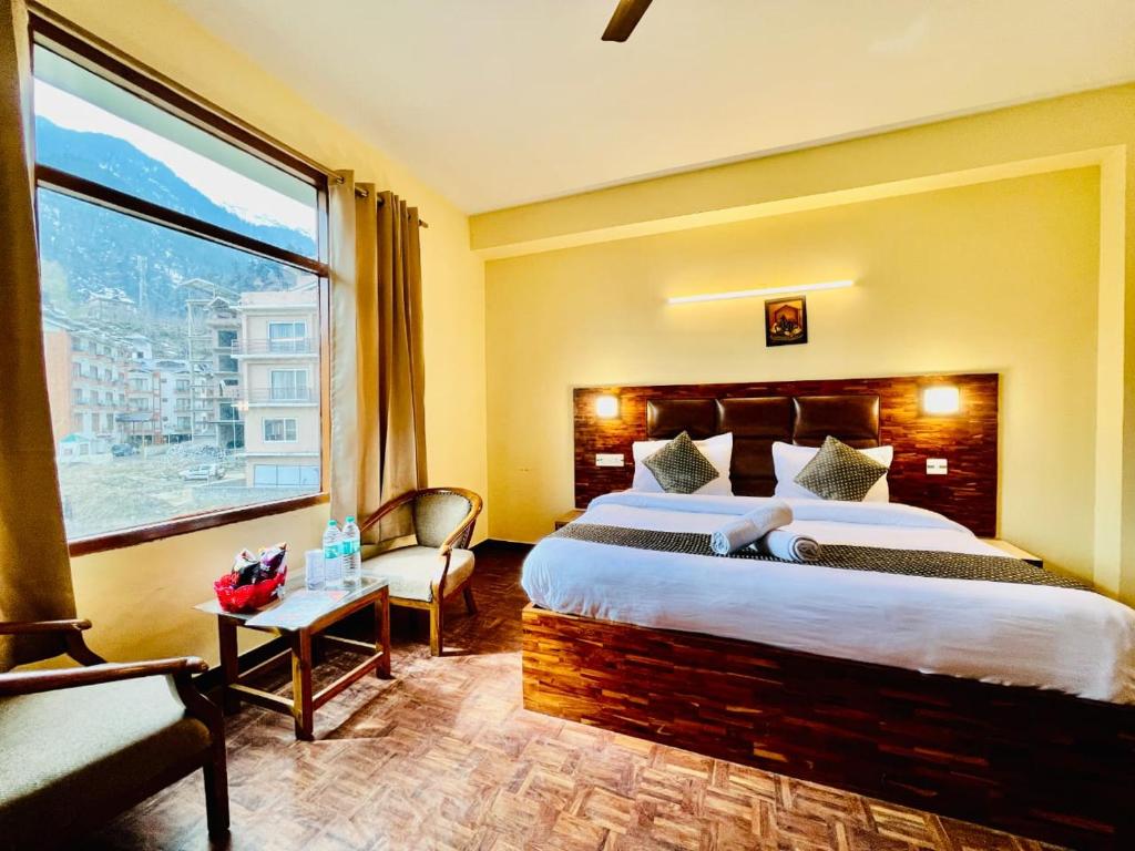 a hotel room with a bed and a large window at Antriksh cottage Manali in Manāli