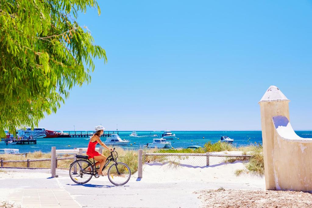 a woman riding a bike on the beach at Stay Rottnest in Rottnest Island
