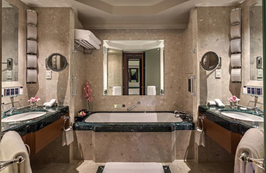a bathroom with two sinks and a bath tub at The Peninsula Bangkok in Bangkok
