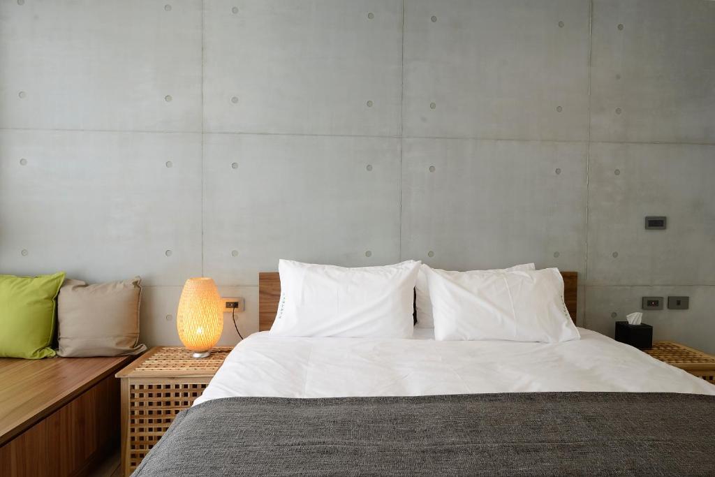 魚池鄉的住宿－日月潭山慕藝旅 Sun Moon Inn，一间卧室配有一张带白色床单和一盏灯的床。