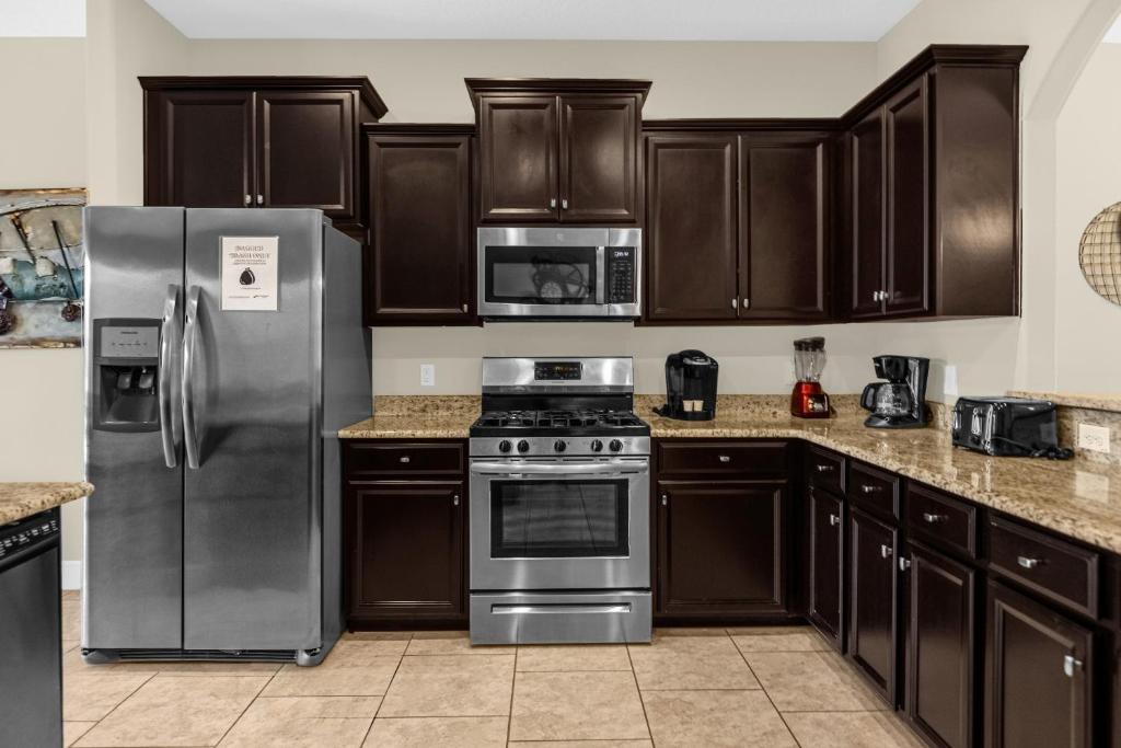 a kitchen with wooden cabinets and stainless steel appliances at 5259-6-WW-Pool&SPA Lazy River&Slides in Davenport