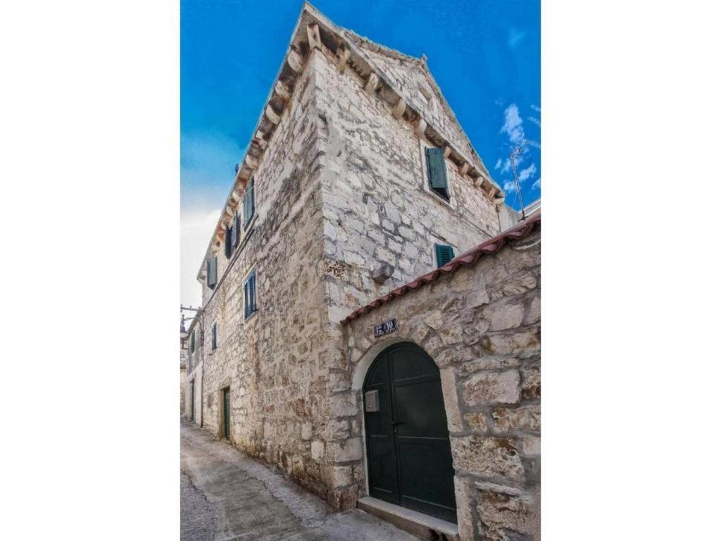 ein altes Steingebäude mit einer Tür auf einer Straße in der Unterkunft Stone Apartment Primosten in Primošten