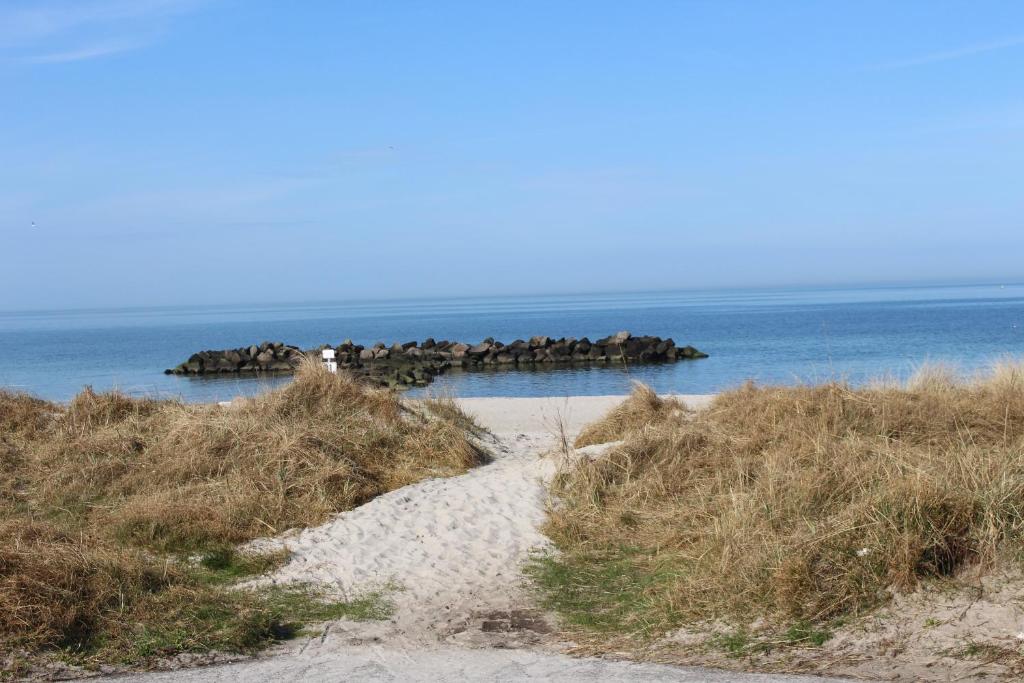 a path to a beach with rocks in the water at Ferienwohnung Iris, Kalifornien, Meerblick, erste Strandreihe in Schönberg