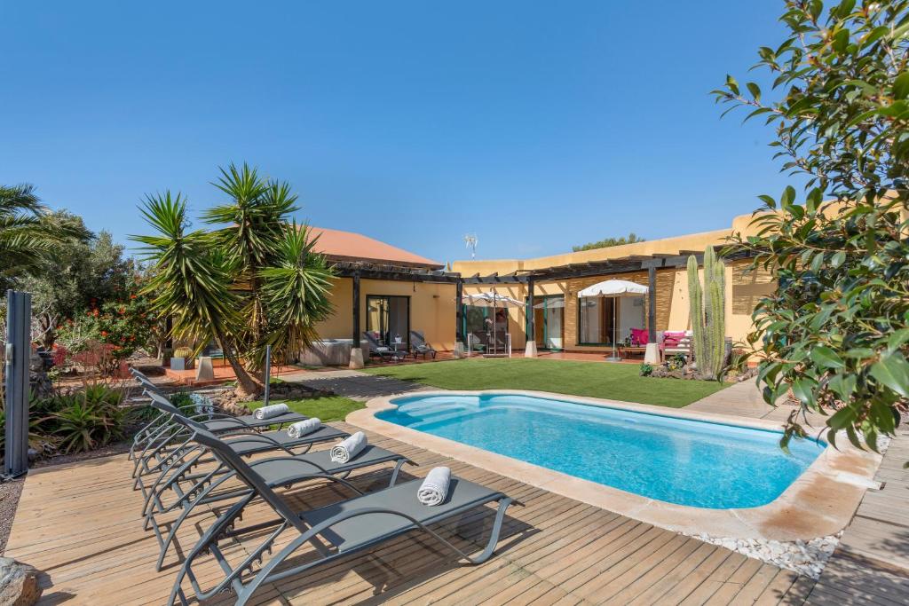 una casa con una piscina con sillas junto a ella en El refugio, en La Oliva