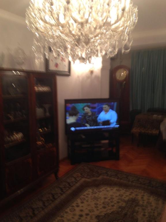 een woonkamer met een televisie en een kroonluchter bij Nobel Avenue 5 Apartment in Baku