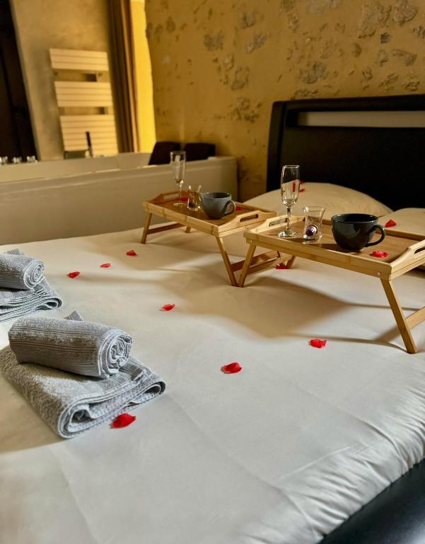 - deux tables sur un lit avec des coeurs rouges au sol dans l'établissement Love Queen SPA DÉTENTE, à Blois