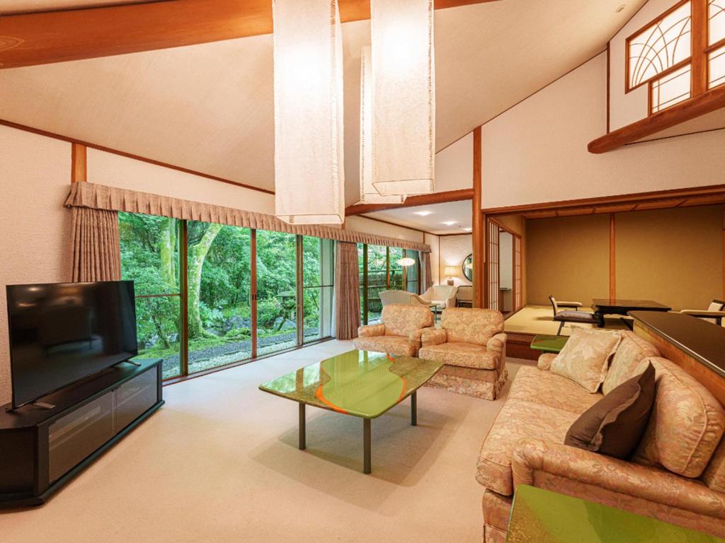 un salon avec un canapé et une télévision dans l'établissement 旅亭 半水盧, à Unzen