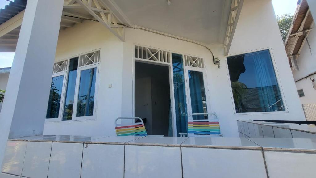 a house with two chairs sitting on the front porch at Palm Cozy Villa in Pasauran