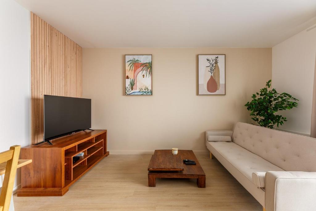 un salon avec un canapé et une télévision à écran plat dans l'établissement L’Oasis Normande - Centre-ville de Rouen, à Rouen