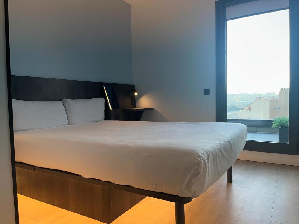 a large bed in a room with a large window at Hs Madrid Centro Atocha in Madrid