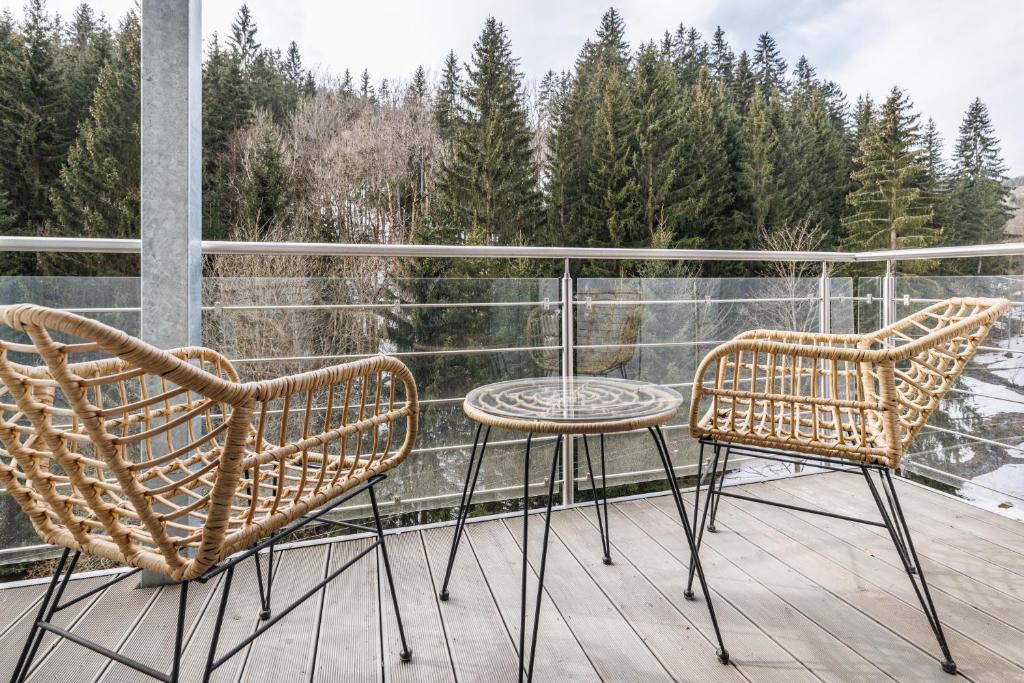 two chairs and a table on a balcony with trees at Jasmínový Ráj in Vítkovice