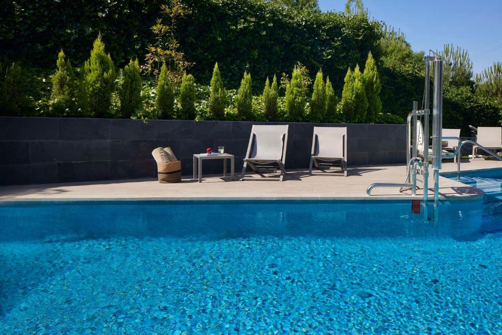 a pool with chairs and a table next to a fence at NH Madrid Ribera del Manzanares in Madrid