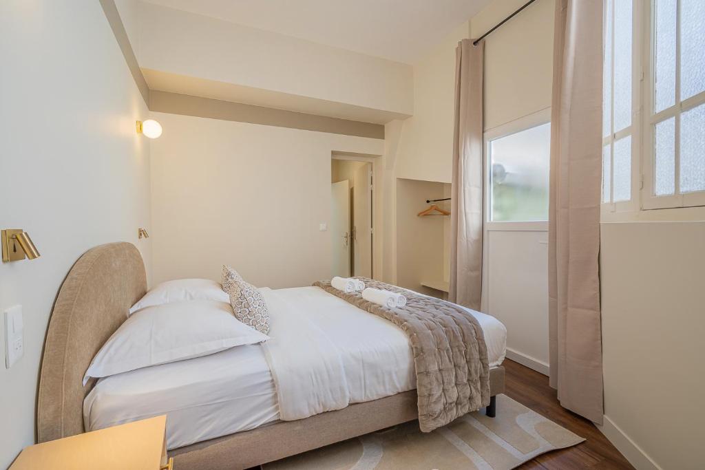 a bedroom with a bed with white sheets and a window at Résidence Levloft in Paris