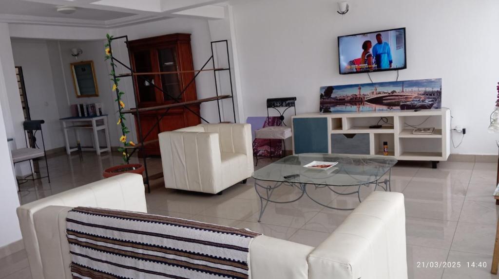 a living room with a glass table and white chairs at résidence le 5eme Ciel in Douala