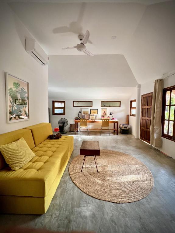 a living room with a yellow couch and a table at PaChaSi Samui Bungalows in Ban Bang Po