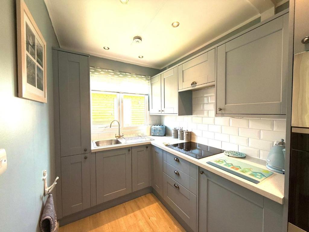 een keuken met witte kasten, een gootsteen en een raam bij Carol's Chalet in Bridlington