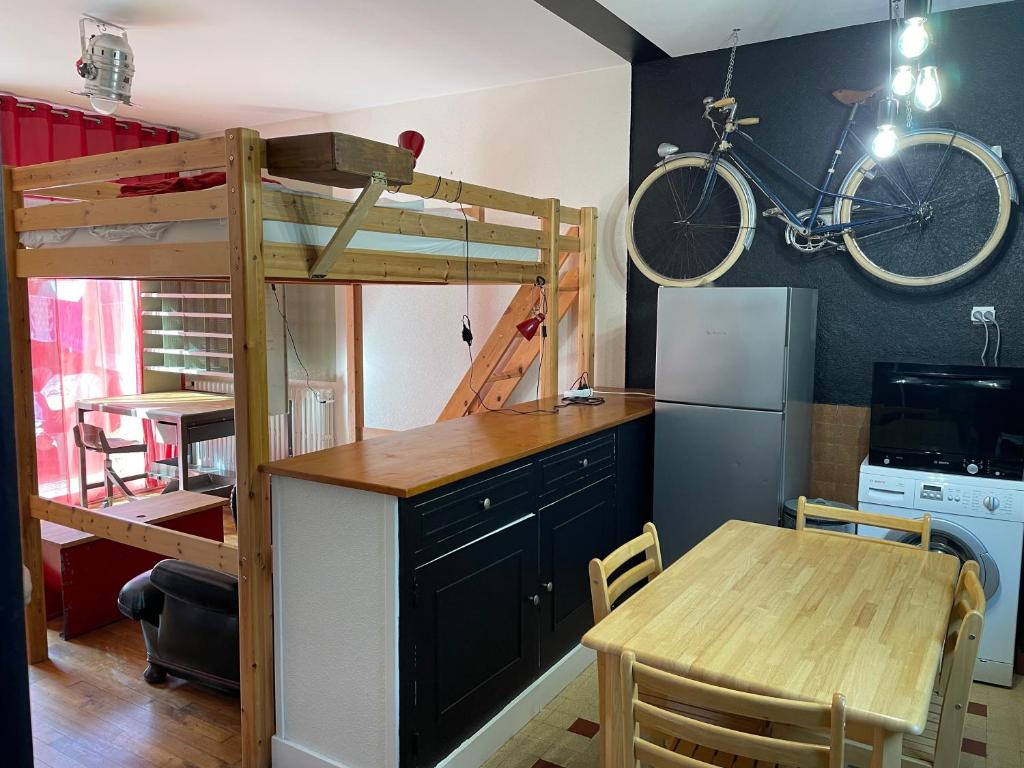 - une cuisine avec une mezzanine, une table et un vélo sur le mur dans l'établissement Studio avec terrasse, salle d'eau et WC partagés, à Lorient
