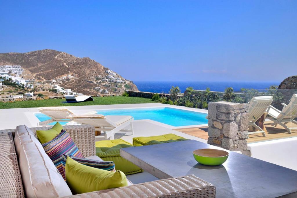 um pátio com uma mesa e cadeiras e uma piscina em Villa Castalia by Thalassa Residence Mykonos em Elia Beach