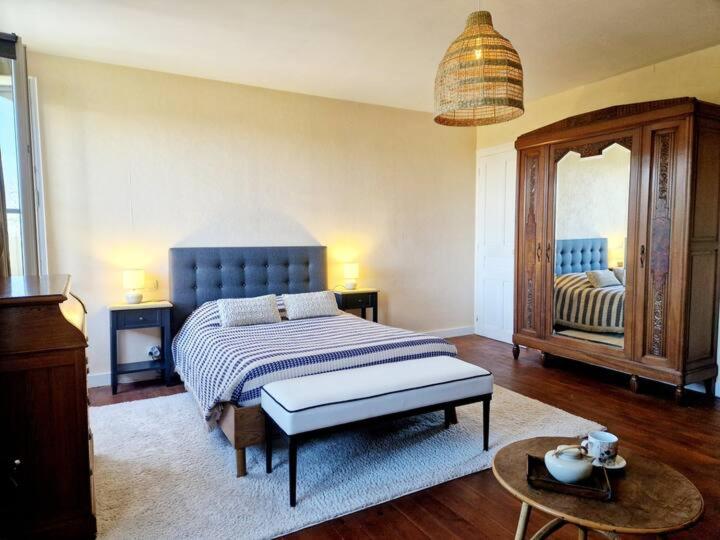 Maison de famille au cœur du bocage normand في Besneville: غرفة نوم بها سرير ومرآة كبيرة