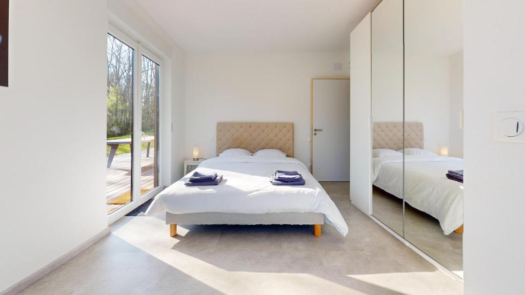 a white bedroom with two beds and a mirror at Le Chalet avec Piscine - Obernai in Obernai