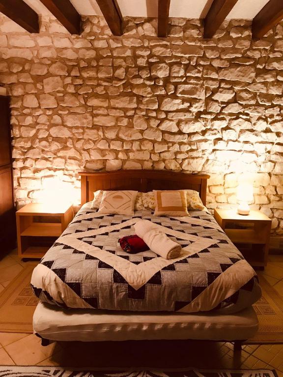 une chambre avec un lit dans un mur de pierre dans l'établissement Maison familiale jardin wifi 17km Beauval, à Villentrois