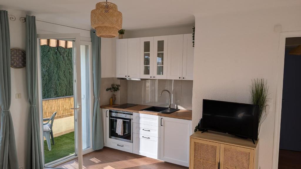 une cuisine avec des armoires blanches et une télévision à écran plat dans l'établissement Les cigales de Fabregas, à La Seyne-sur-Mer