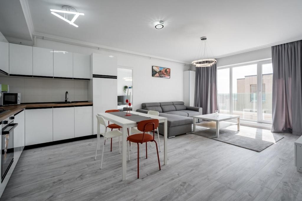 Una cocina y una sala de estar con mesa y sillas. en Rose Residence 1-1BR Apt-Parking, en Voluntari