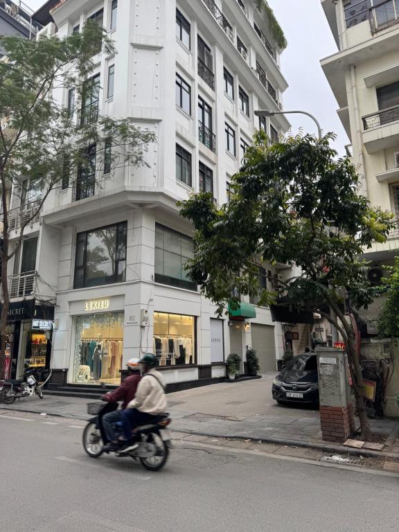 two people riding a motorcycle down a city street at Studio 2 Byhomelinh Phố Cổ Hoàn Kiếm in Hanoi