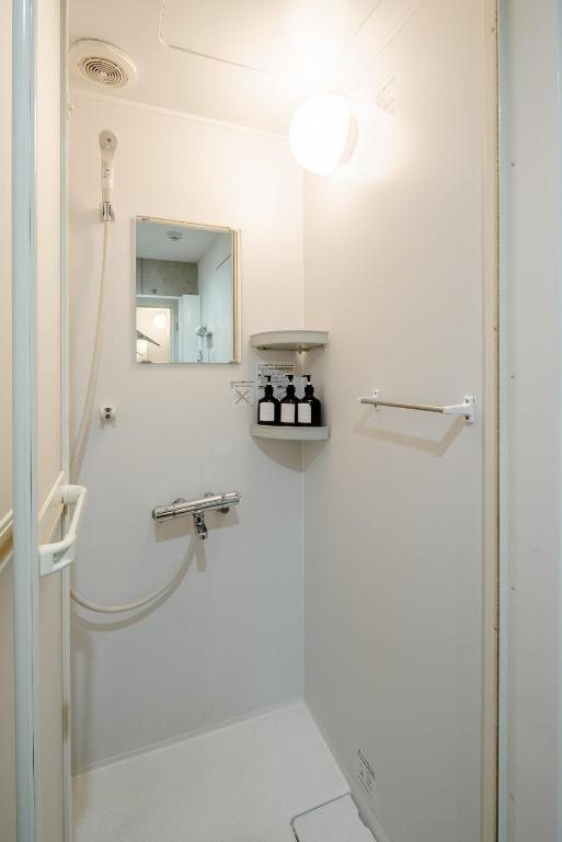 a white bathroom with a shower and a mirror at 原田屋Hotel 3F in Tokyo