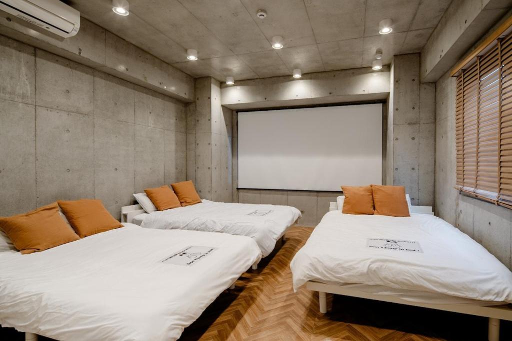 three beds in a room with a projection screen at 原田屋Hotel 3F in Tokyo