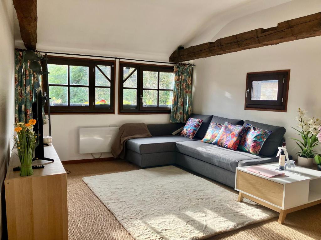 a living room with a gray couch and windows at Paloma in Figeac