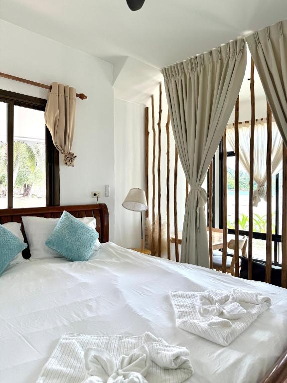 a bedroom with a bed with white sheets and a window at Chic house on the beach in Mae Haad