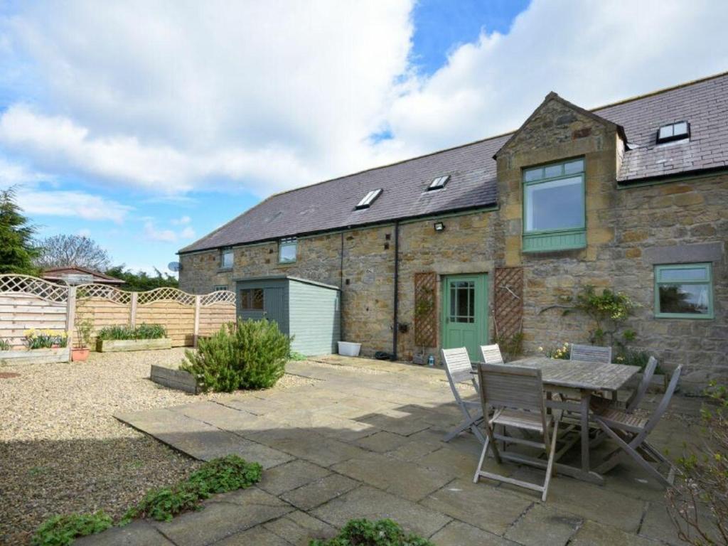 une maison en pierre avec une table et des chaises dans la cour dans l'établissement Croft Cottage, à Alnwick