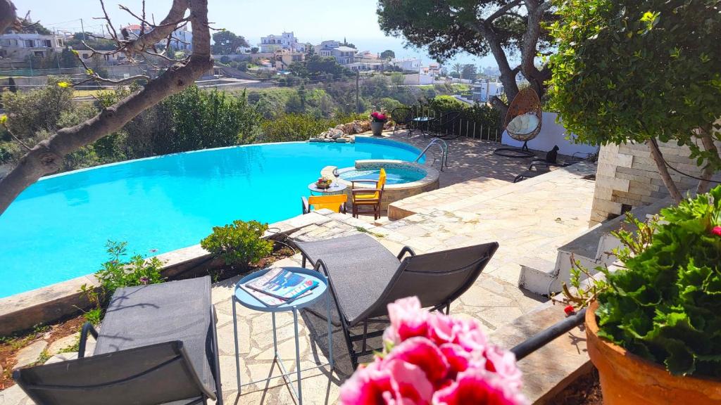 una piscina con sillas, una mesa y una persona en Complex HARMONY with infinity pool, en Kalívia Thorikoú