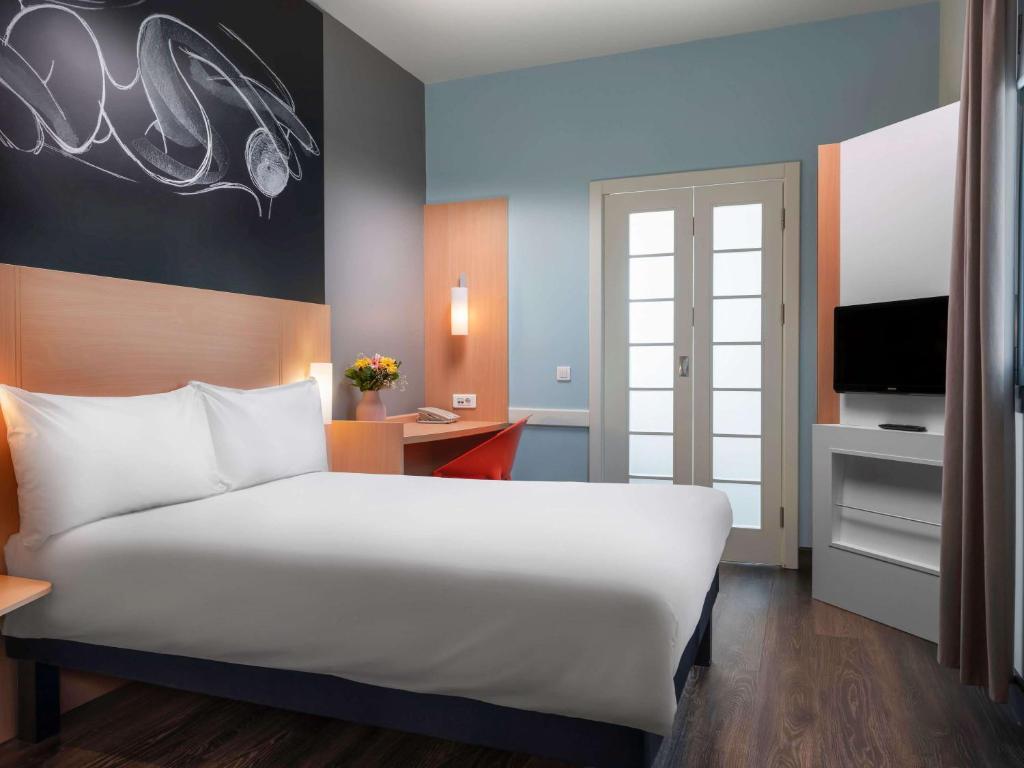 a bedroom with a large white bed and a desk at ibis Ankara Airport Hotel in Ankara
