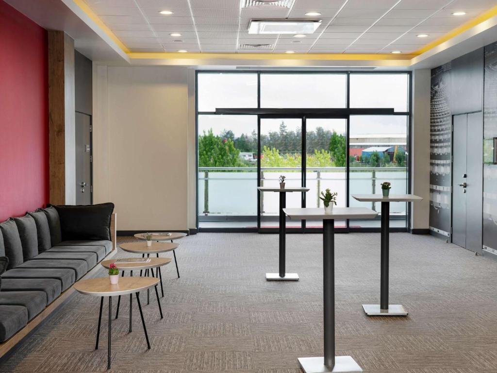 a lobby with a couch and tables and a large window at ibis Ankara Airport Hotel in Ankara