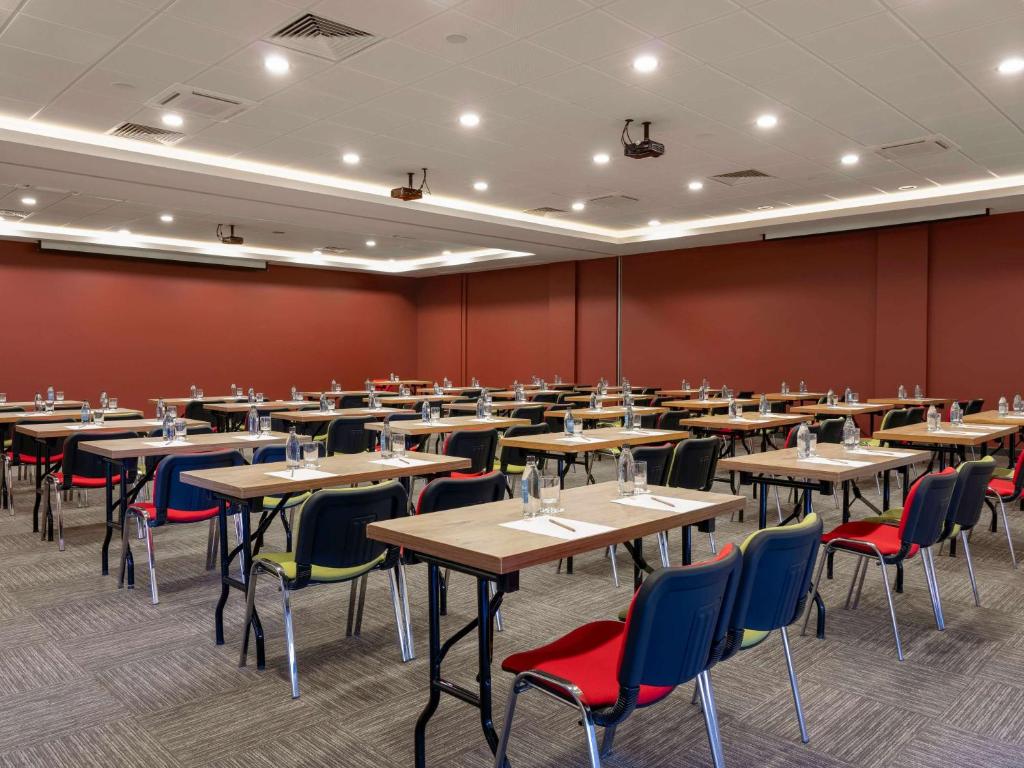 a large room with tables and chairs and red walls at ibis Ankara Airport Hotel in Ankara