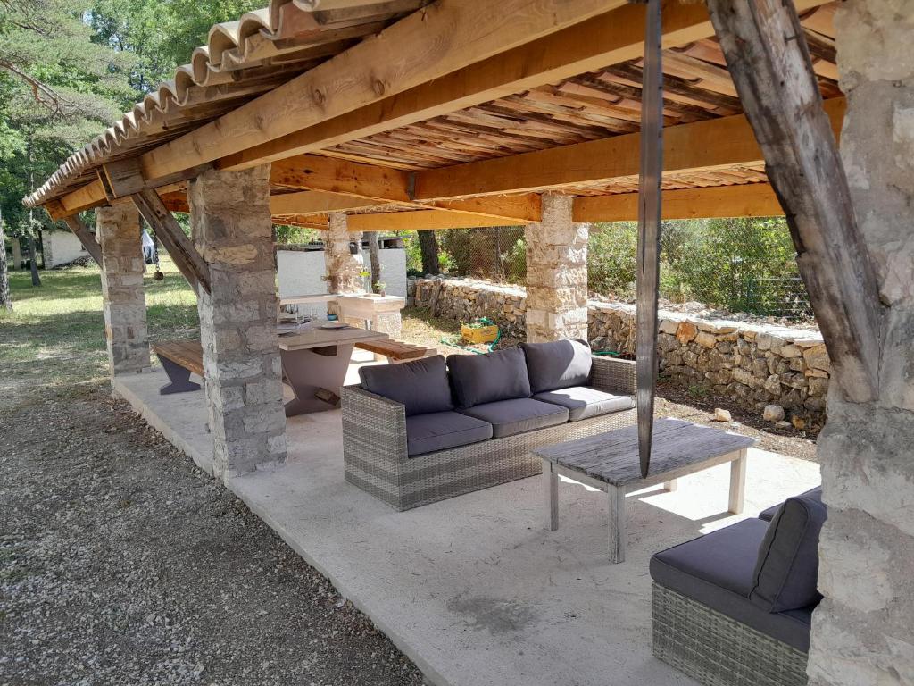 a covered patio with a couch and a table at MAISON au calme en pleine nature 2 PERSONNES in Fayence