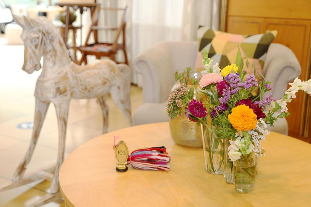 a table with vases of flowers and a plastic horse on it at Greifensteiner Hof in Würzburg