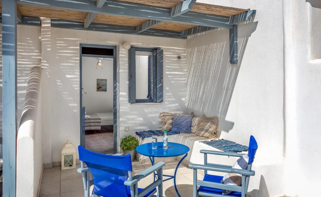 eine Terrasse mit blauen Stühlen, einem Tisch und einem Sofa in der Unterkunft Althea Studios in Donousa