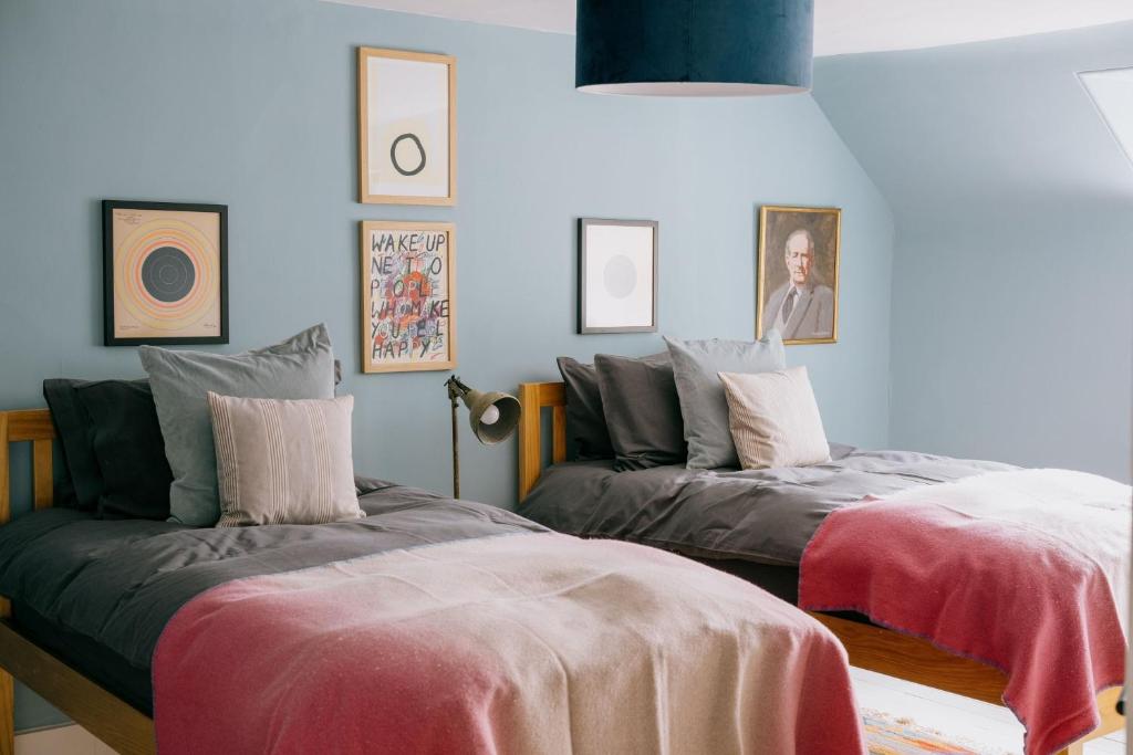 a bedroom with two beds and pictures on the wall at Gamekeeper's Cottage in Banchory