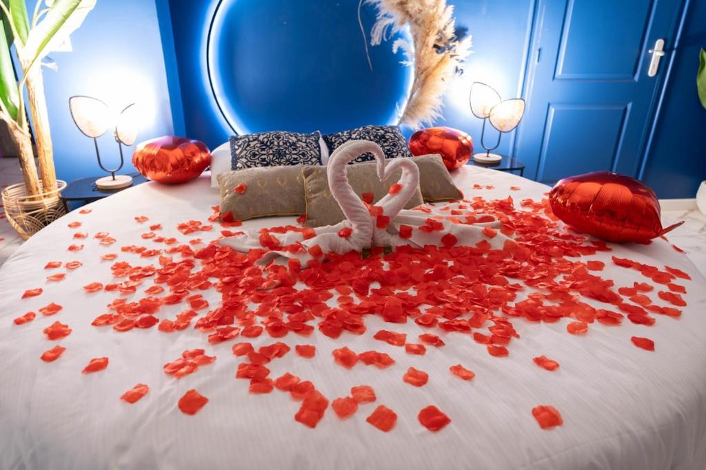 - un lit avec des pétales rouges et une chambre avec un mur bleu dans l'établissement Chambre avec Balnéo, centre ville de Nice, à Nice