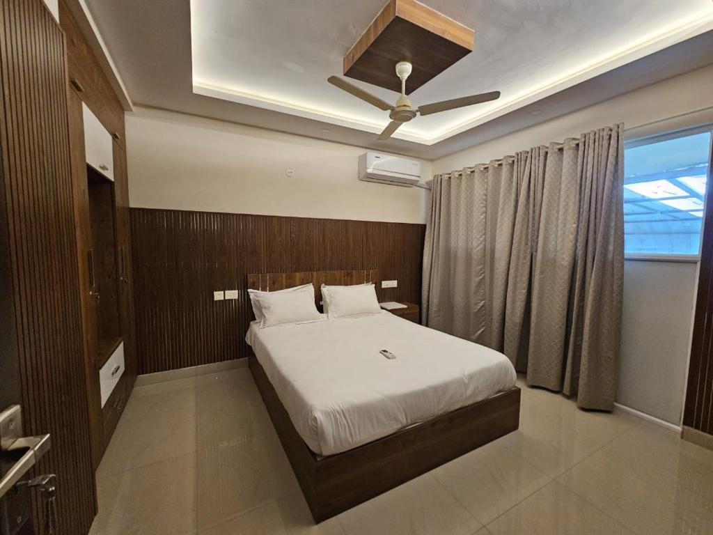 Un dormitorio con una cama blanca y una ventana. en Laura Airport Suits & Apartments, en Nedumbassery
