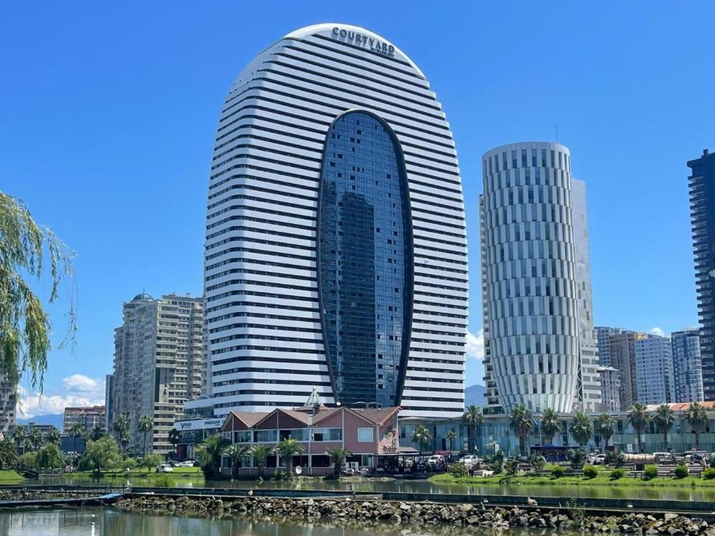 a tall building in a city next to a river at Beach Apartment in Batumi