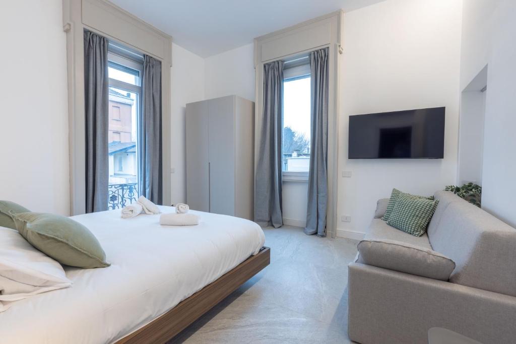 una camera da letto bianca con un letto e un divano di Villa Magenta Rho Fair & Station a Rho