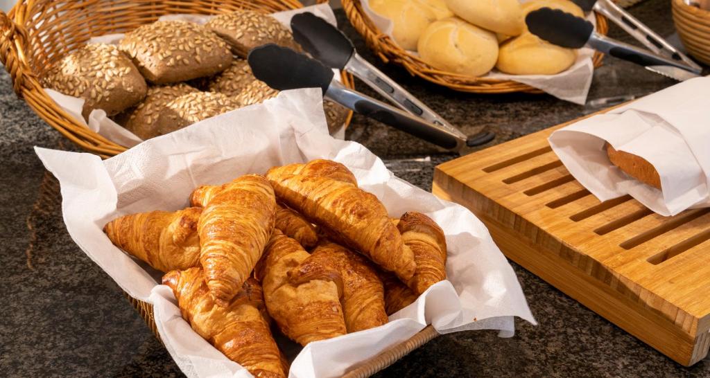a basket of bread and pastries on a table at PLAZA INN Regensburg in Regensburg